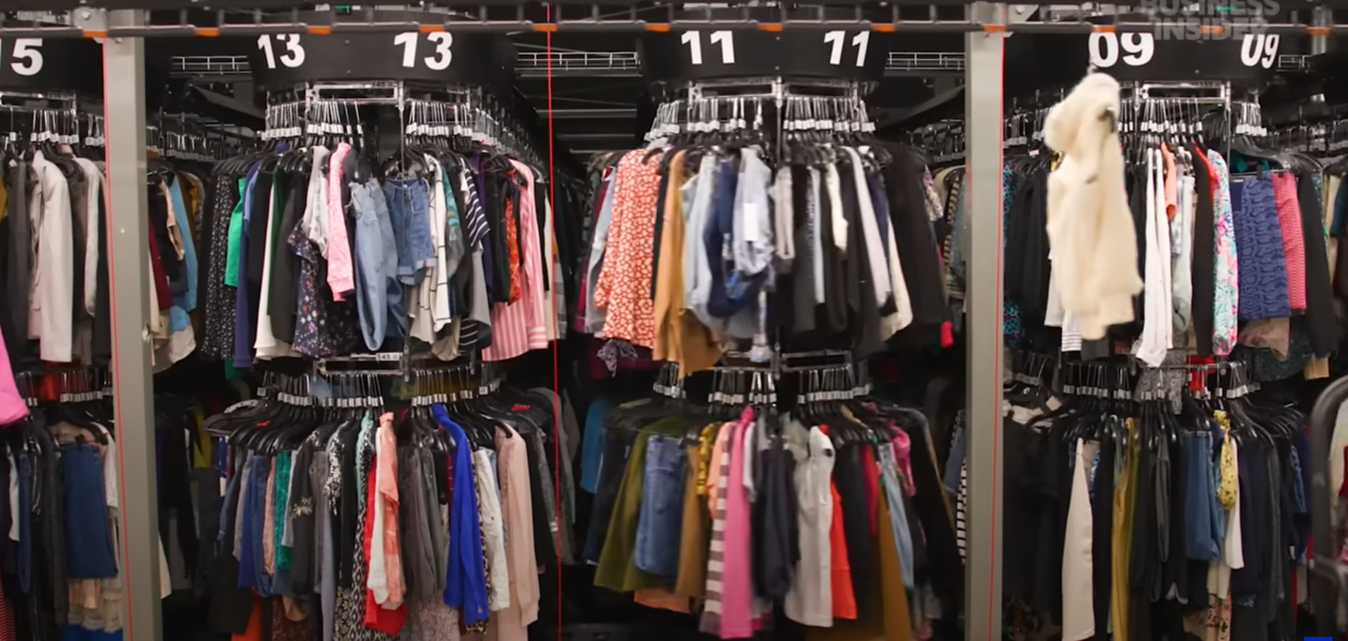 ThredUp warehouse with organized clothing racks showing the scale of AI-powered fashion processing - thousands of garments systematically arranged for resale